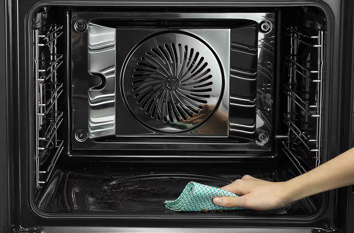 Hand veegt bodem van oven na pyrolyse schoon