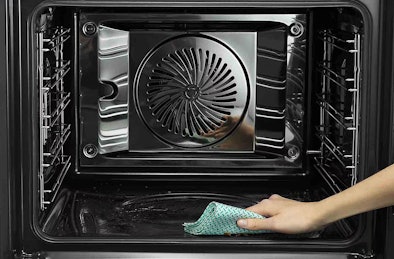 Hand veegt bodem van oven na pyrolyse schoon