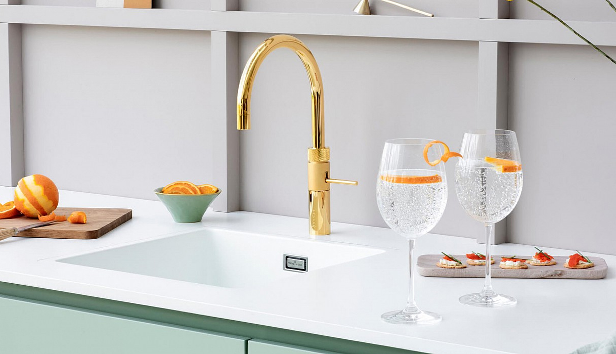 Gouden Quooker Fusion Round kraan met twee glazen bruisend water en sinaasappel