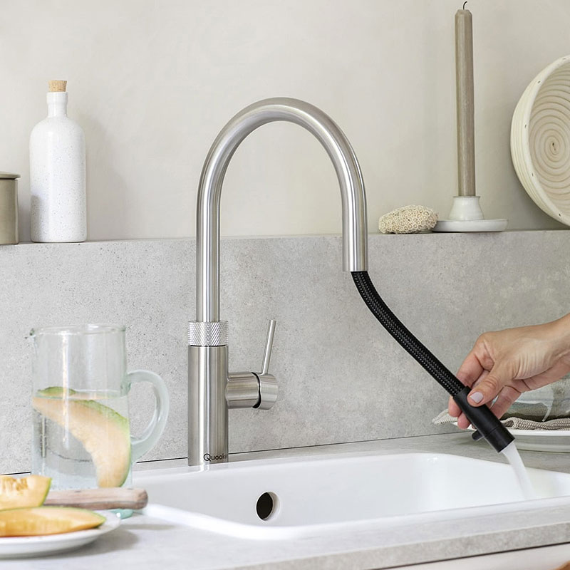 Quooker Flex RVS met uittrekbare slang in gebruik — hand trekt de flexibele slang uit boven witte spoelbak