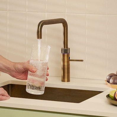 Quooker Fusion Square Messing Patina — bruisend water wordt getapt in een glas in moderne keuken