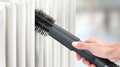 Radiatorborstel Miele SHB 30 in gebruik tussen radiatorlamellen met platte vorm voor smalle ruimtes en kieren