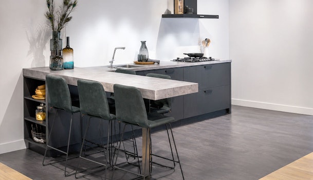 Moderne rechte keuken met verlengd barblad en drie barkrukken in donkere uitvoering, geplaatst in een open woonruimte met veel vrije loopruimte.