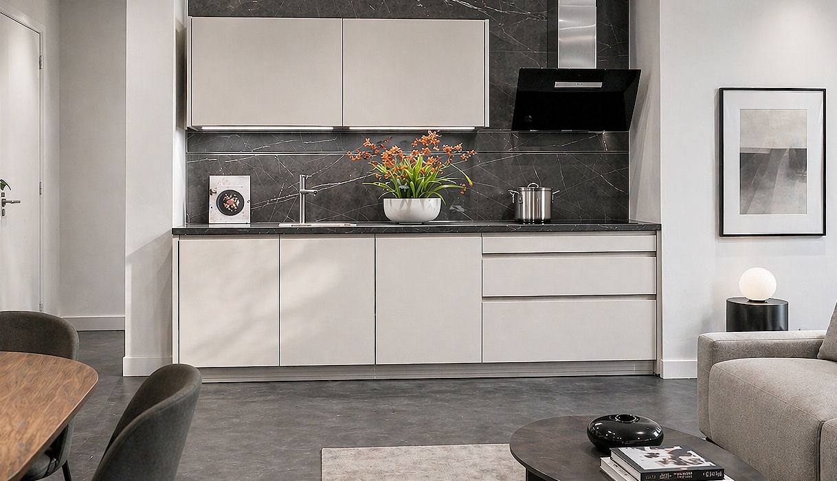 Rechte keuken van 3 meter met witte fronten, donkere marmerlook achterwand en zithoek