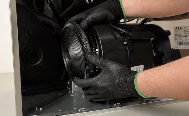 Monteur met werkhandschoenen vervangt de motor van een AEG afzuigkap tijdens reparatie