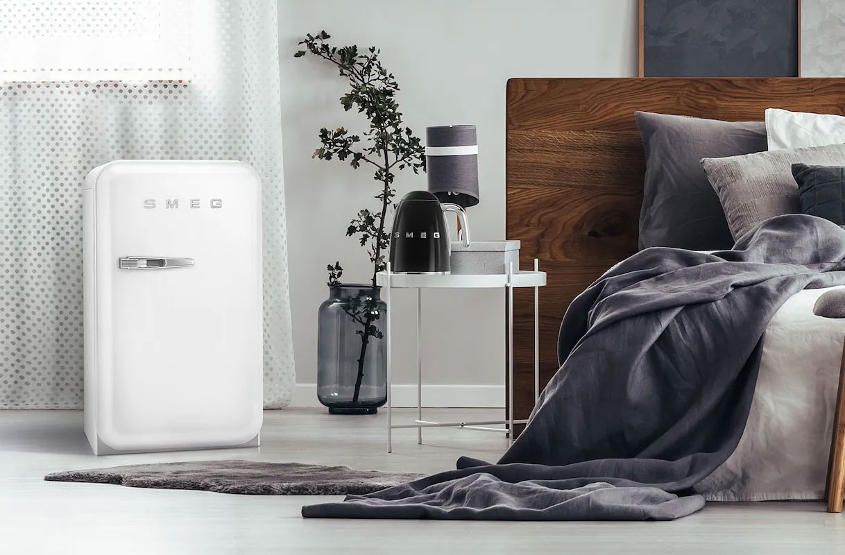 Witte retro tafelmodel koelkast van Smeg met chromen handgreep in een stijlvolle slaapkamer