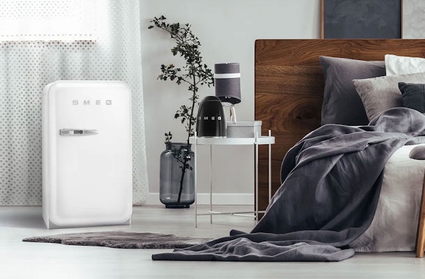 Witte retro tafelmodel koelkast van Smeg met chromen handgreep in een stijlvolle slaapkamer