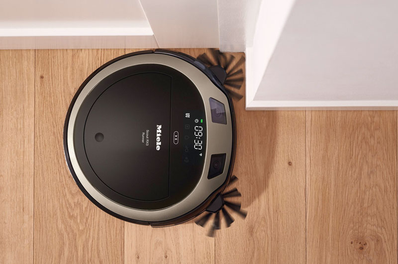 Robotstofzuiger met accu op houten vloer met digitaal display en oplaadstation