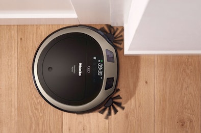 Robotstofzuiger met accu op houten vloer met digitaal display en oplaadstation