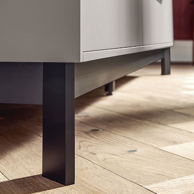 Robuuste matzwarte poot onder kast