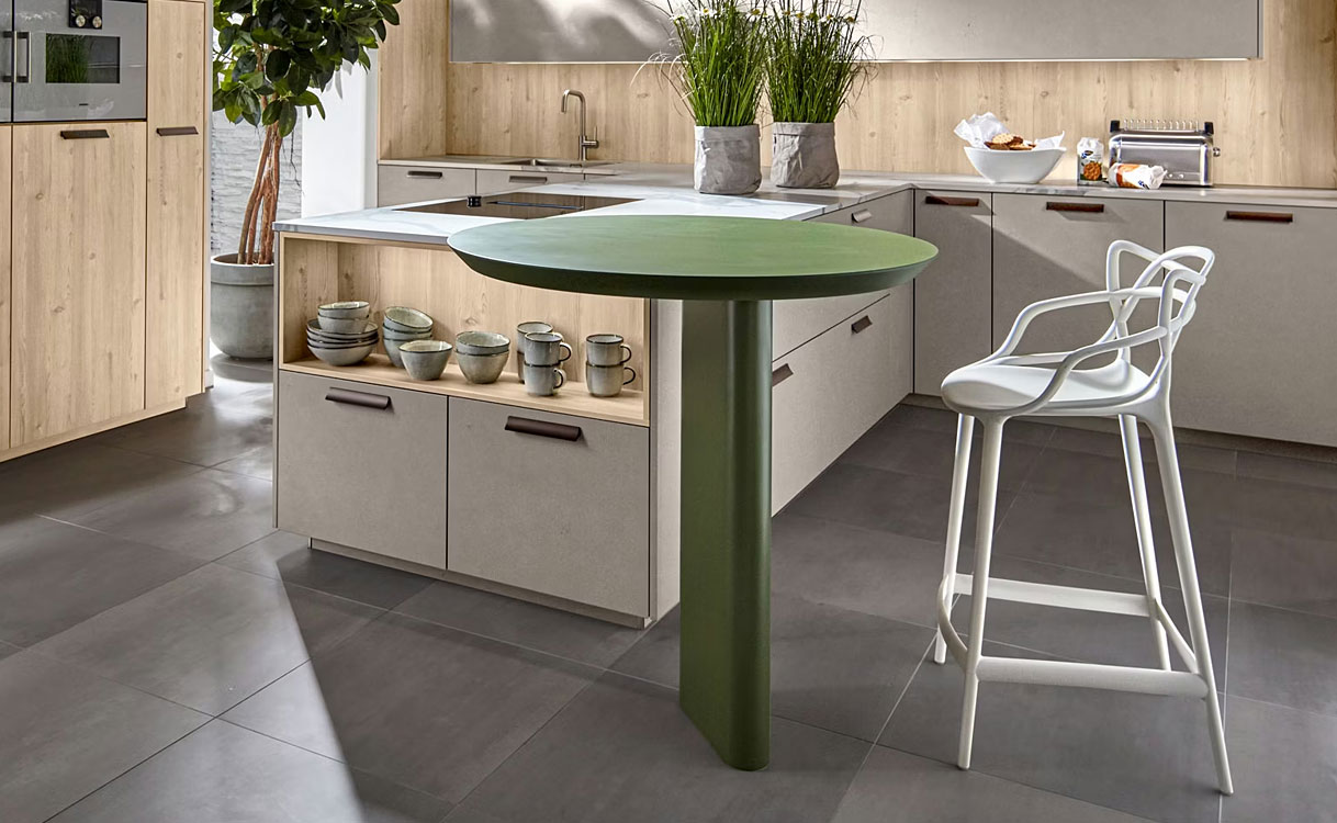 Kookeiland met rond tafelblad op centrale poot, geïntegreerd in moderne keuken met lichte houttinten