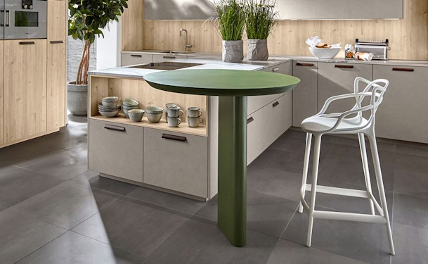 Kookeiland met rond tafelblad op centrale poot, geïntegreerd in moderne keuken met lichte houttinten