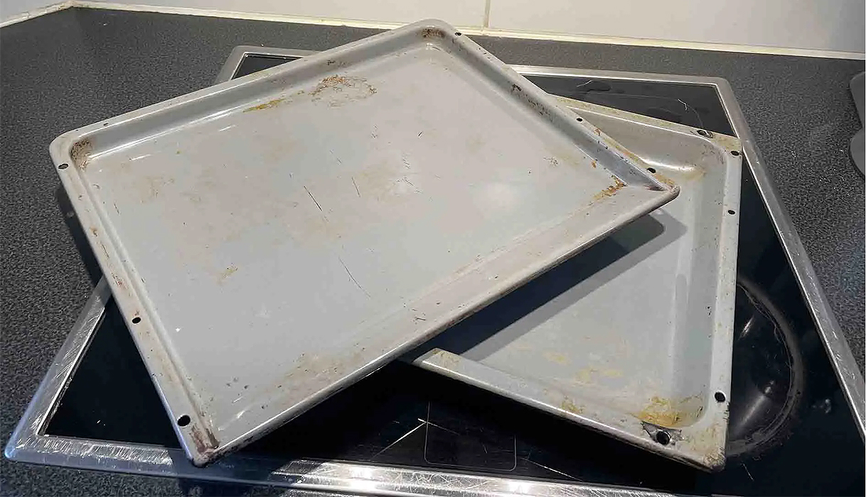 Vuil geworden bakplaten op een kookplaat, klaar om gereinigd te worden