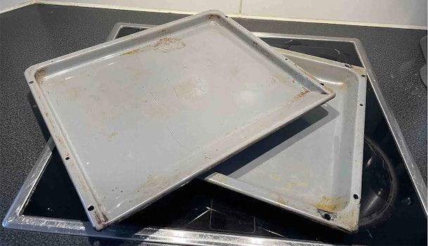 Vuil geworden bakplaten op een kookplaat, klaar om gereinigd te worden