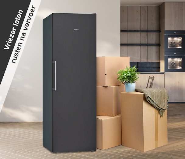 Staande Siemens-vriezer in een nieuwe woning, omringd door verhuisdozen, klaar om te rusten na transport.