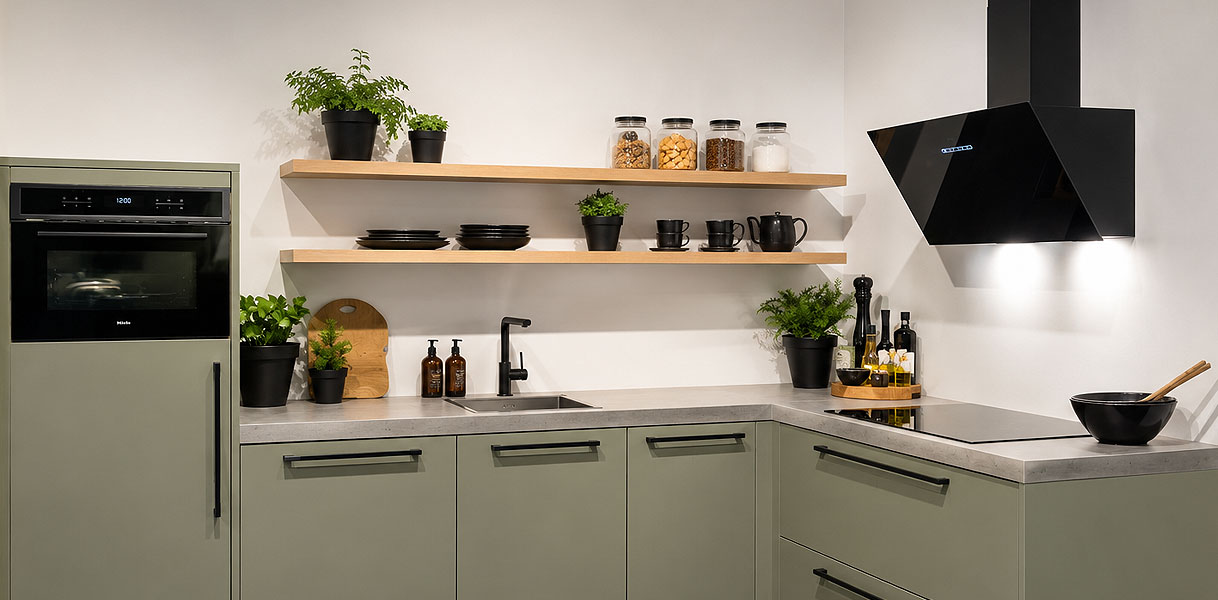 Scandinavische keuken met saliegroene onderkasten, licht houten wandplanken en keramisch werkblad