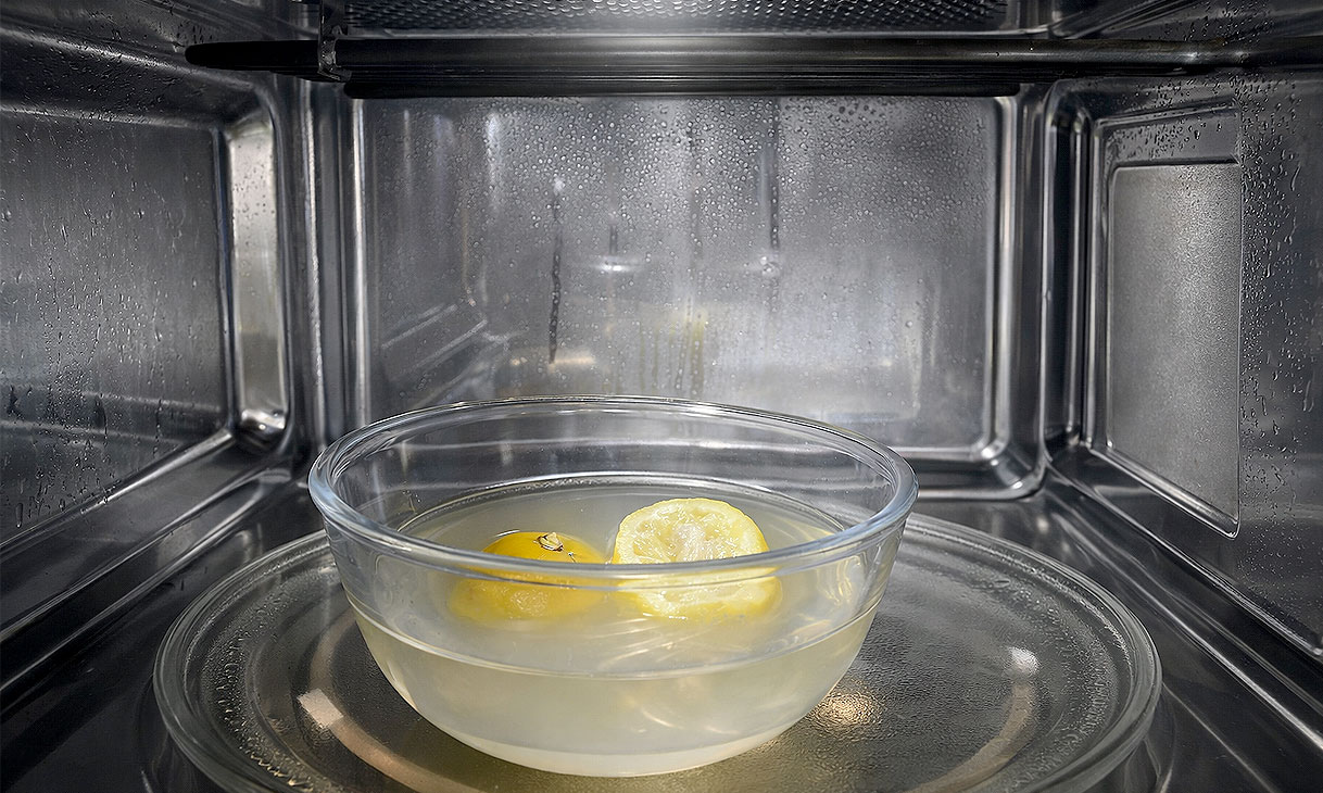 Kom met citroenhelften in water in een magnetron die stoom produceert om vuil los te weken