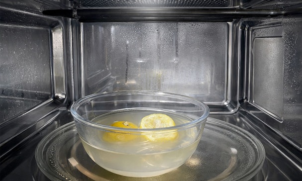 Kom met citroenhelften in water in een magnetron die stoom produceert om vuil los te weken