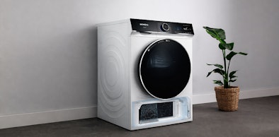 Siemens droger met geopende selfCleaning Condensor lade in moderne wasruimte met plant