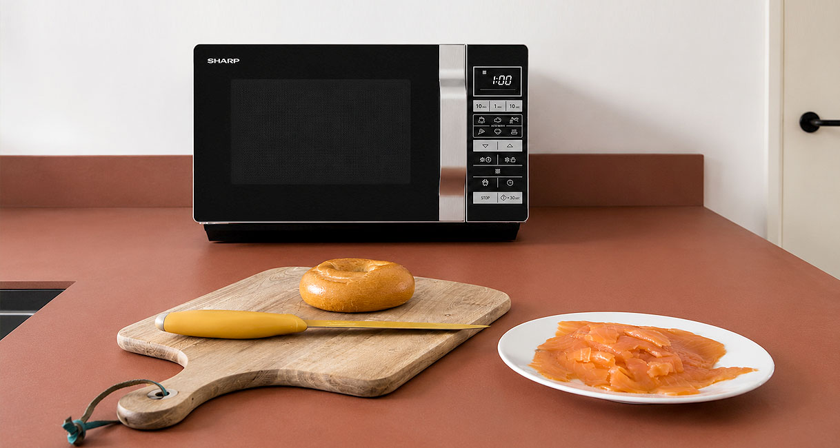Compacte solo magnetron op het aanrecht met een bagel en zalm op de voorgrond