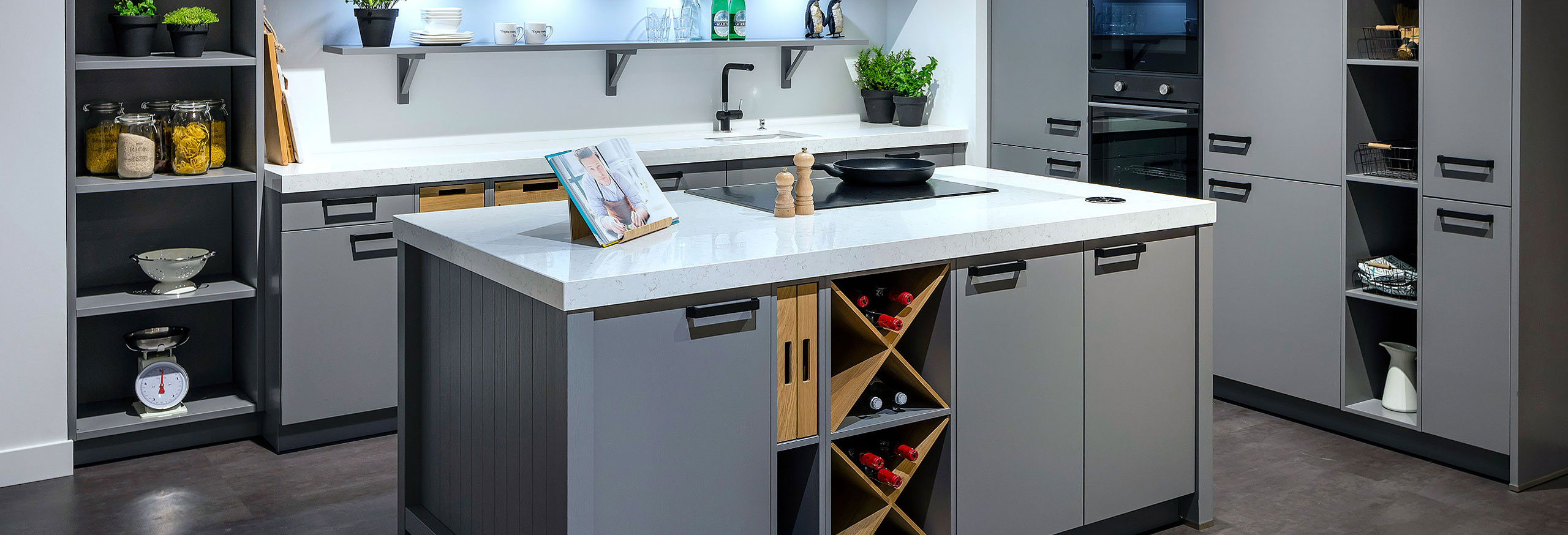 Strakke grijze showroom eilandkeuken met houten elementen