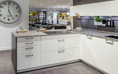 Strakke hoogglans showroomkeuken met marmerlook kastenwand