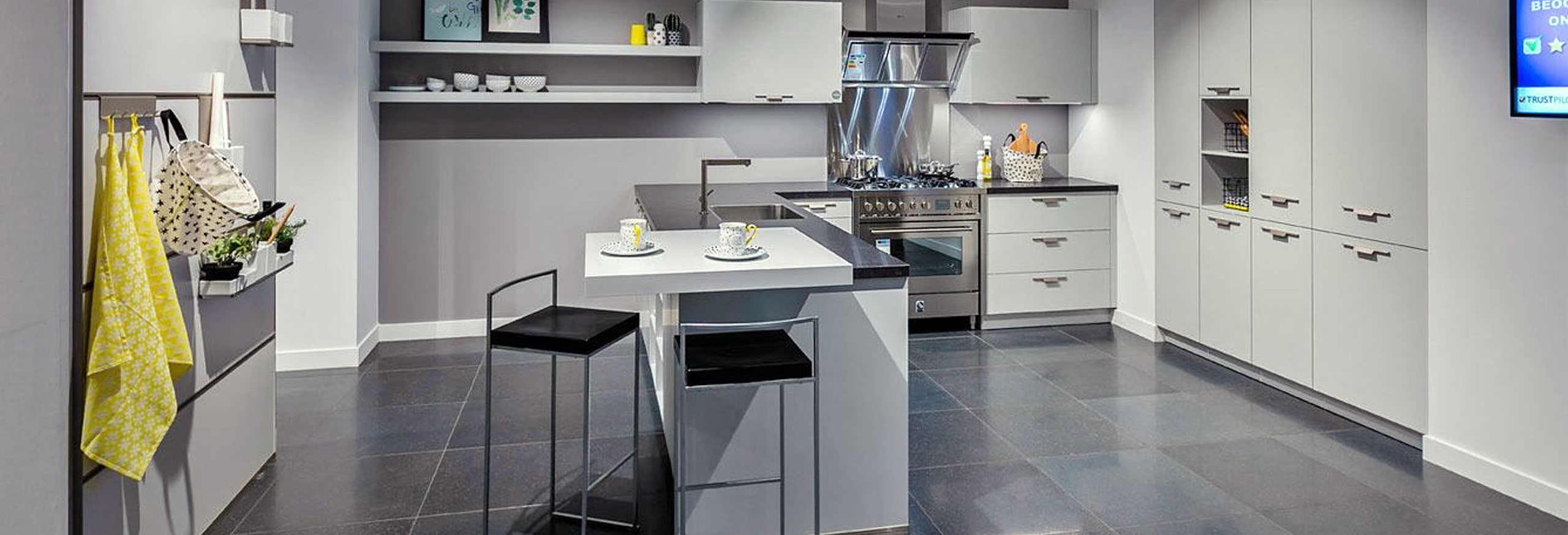 Strakke L-showroomkeuken met RVS fornuis