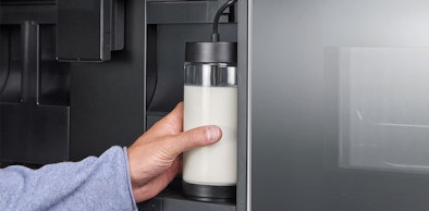 Hand plaatst de melkcontainer in een Siemens inbouw koffieautomaat die zelf herkent hoeveel melk erin zit