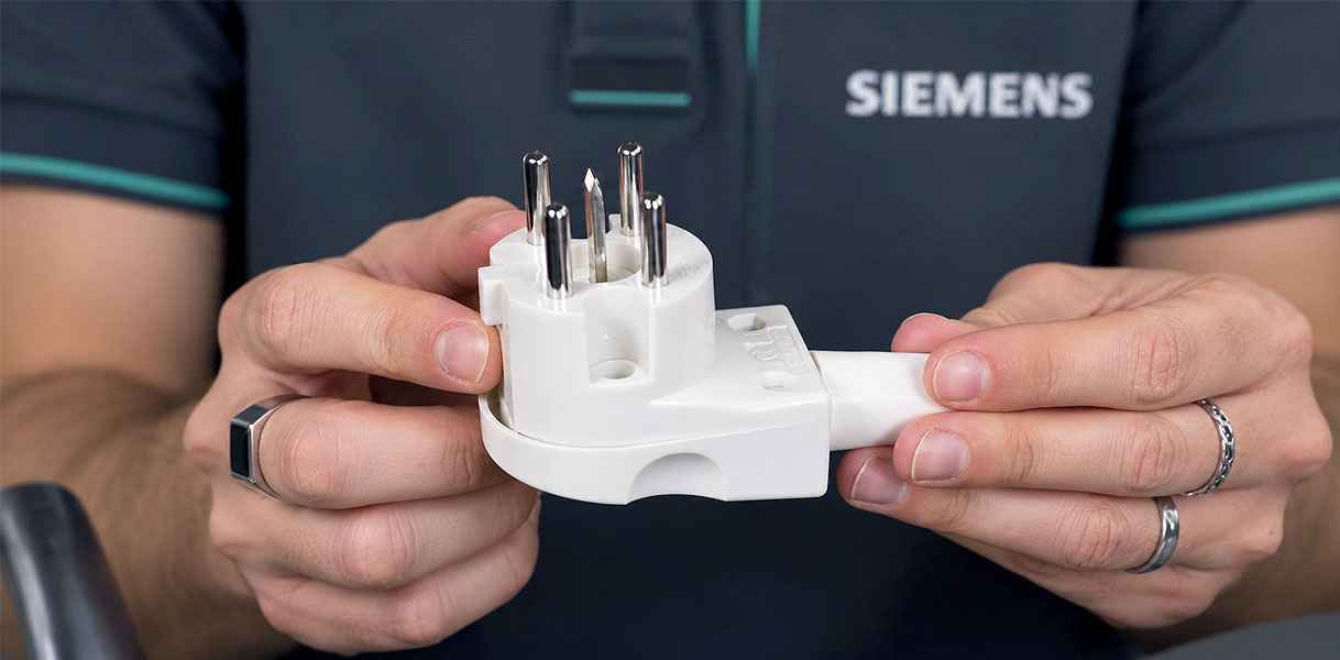 Monteur toont een Perilex stekker voor de aansluiting van een Siemens inductie kookplaat