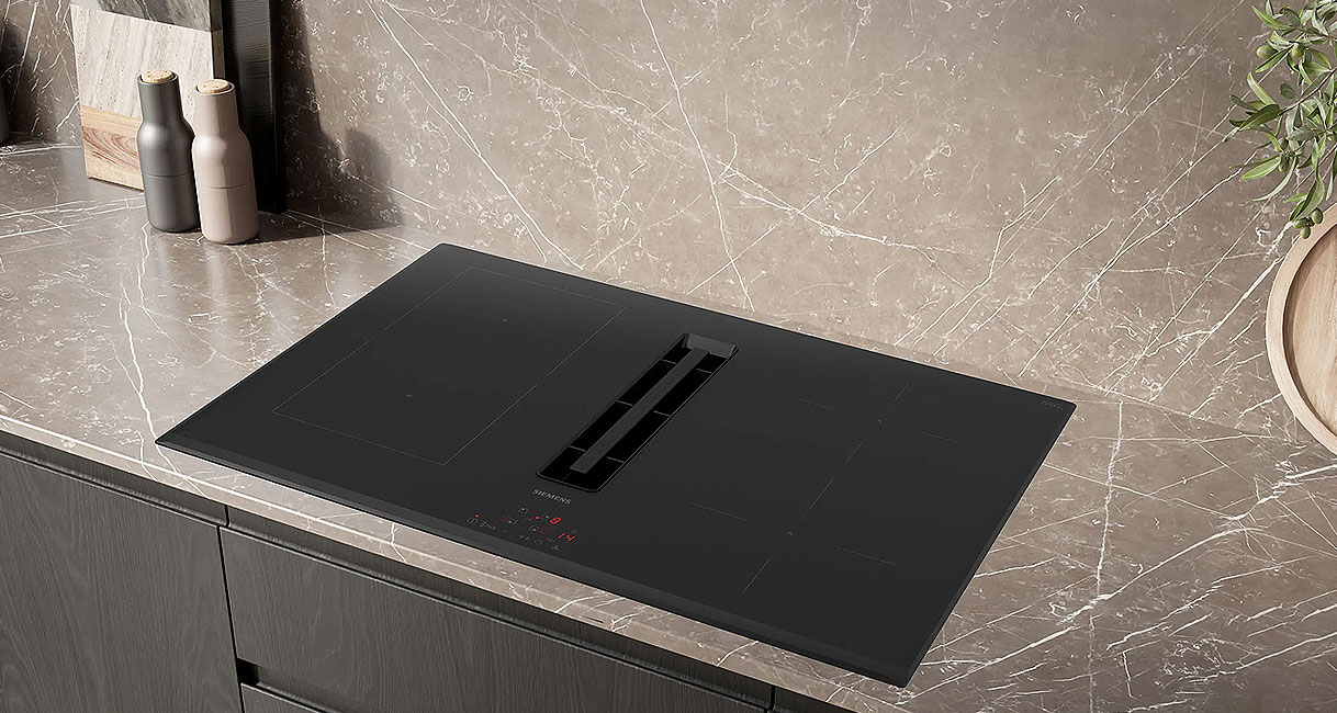 Siemens iQ300 inductiekookplaat met geïntegreerde afzuiging ingebouwd in een donker keukenblad