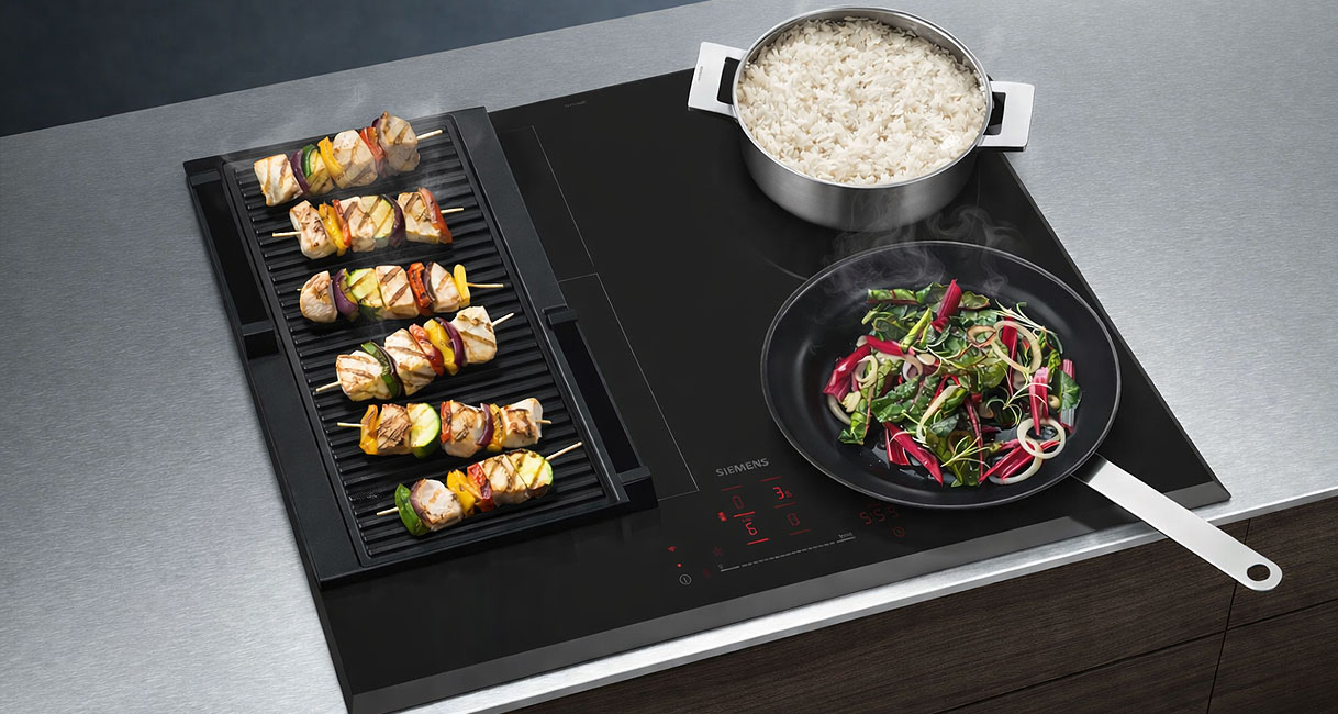 Siemens iQ500 inductiekookplaat met afzuiging en FryingSensor Pro met pannen op het kookoppervlak