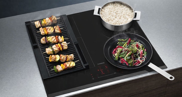 Siemens iQ500 inductiekookplaat met afzuiging en FryingSensor Pro met pannen op het kookoppervlak