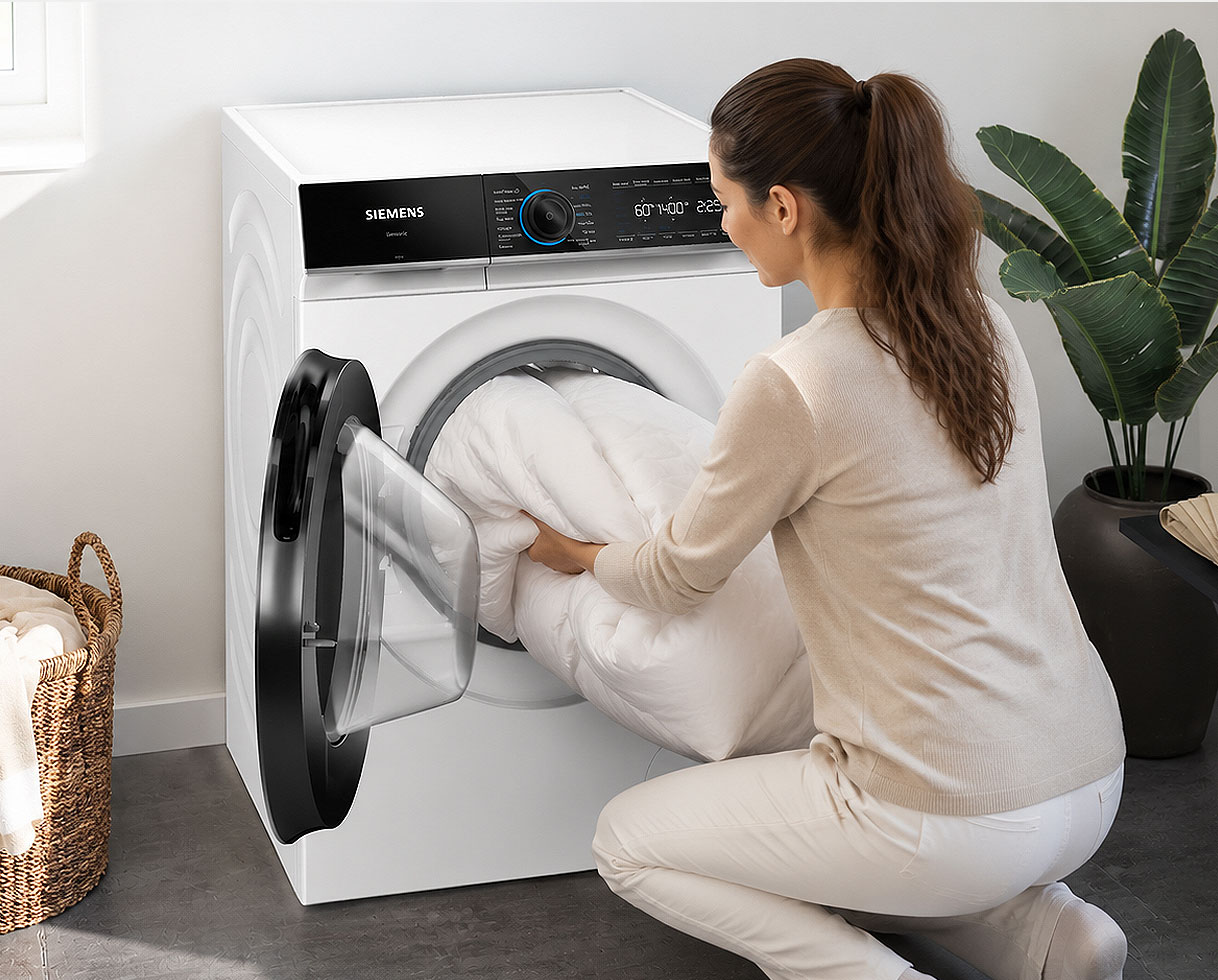 Vrouw laadt een tweepersoons dekbed in de trommel van een Siemens wasmachine van 10 kg