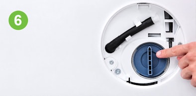 Vinger draait het schoongemaakte filter terug in het pomphuis van een Siemens wasmachine