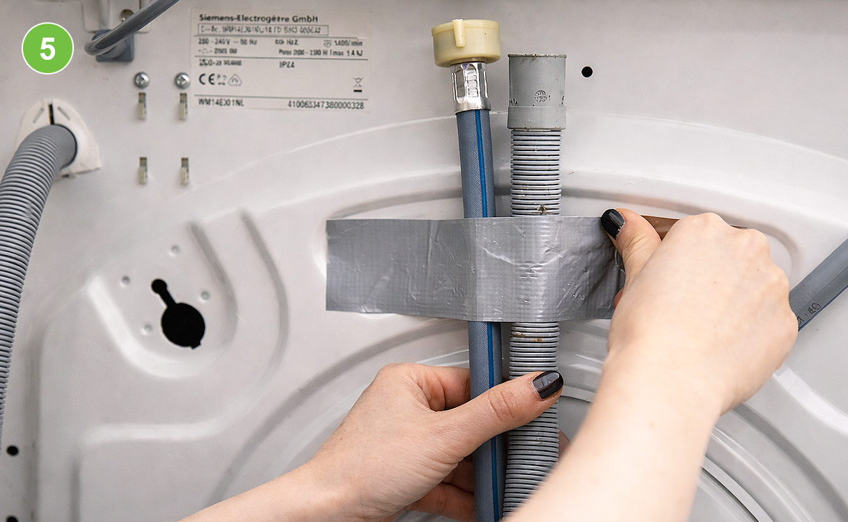 Toevoer- en afvoerslang van een wasmachine vastgezet met ducttape aan de achterkant