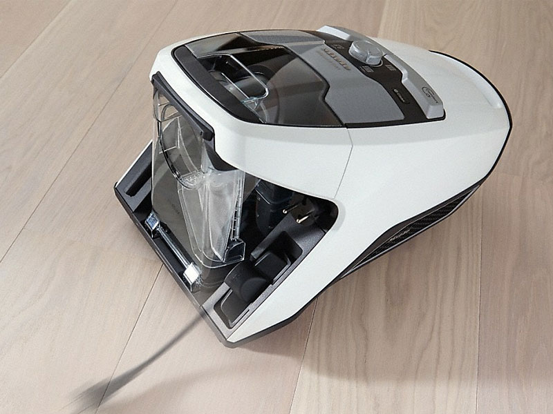 Zakloze sleepstofzuiger op laminaatvloer met instelbare zuigkracht en opzetstukken voor harde vloeren