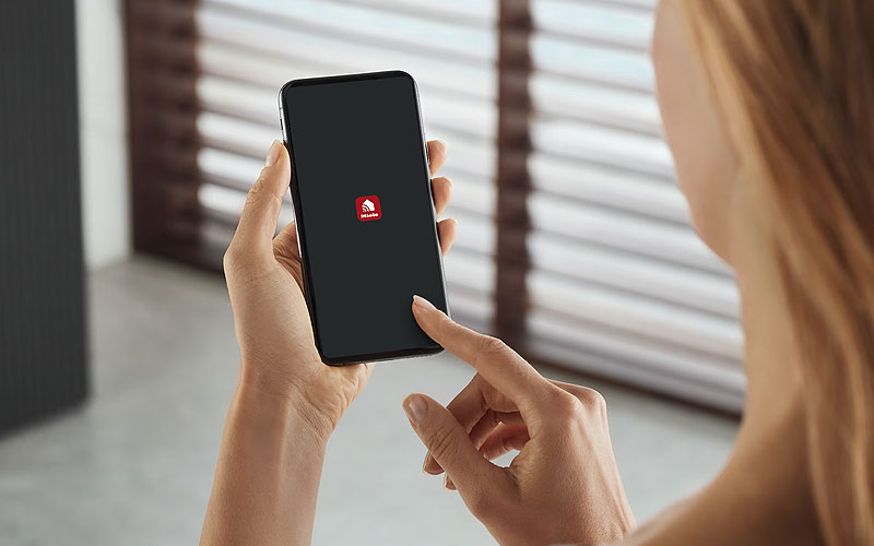 Vrouw bedient Miele combimagnetron via Miele@home app op smartphone