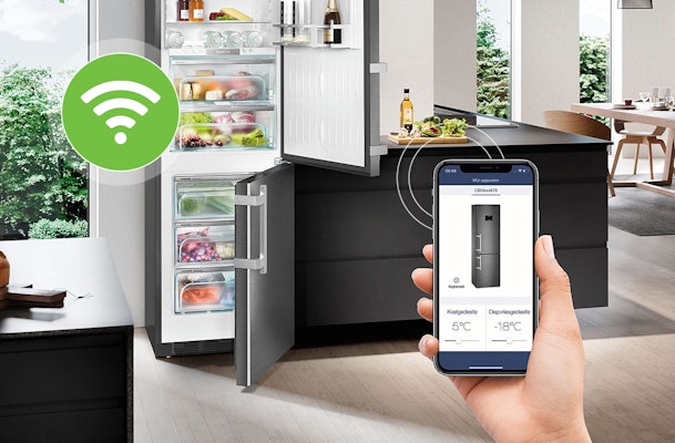 Persoon bedient slimme koelkast met smartphone via WiFi-app om temperatuur van koel- en vriesgedeelte aan te passen
