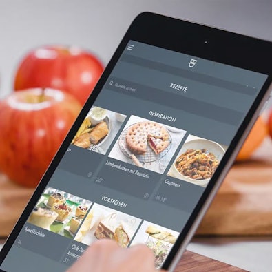 Tablet met V-ZUG Home app; slimme connectiviteit en firmware-updates voor toekomstbestendige koelkasten met remote monitoring en diagnostiek.