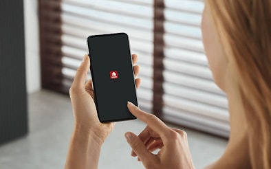 Vrouw gebruikt smartphone met Miele@home app om slimme Miele huishoudelijke apparaten te bedienen via wifi en de Miele Cloud.