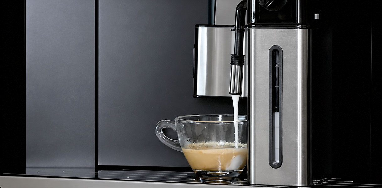 Uitneembare melkkan van een SMEG koffie volautomaat schuimt melk op voor een cappuccino