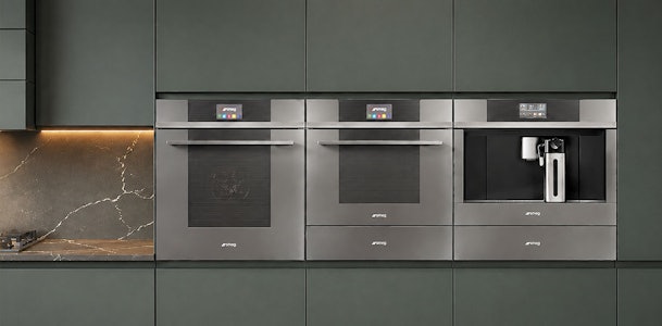 Twee Smeg ovens en koffiemachine uit de strakke Linea designlijn in een groene keukenwand