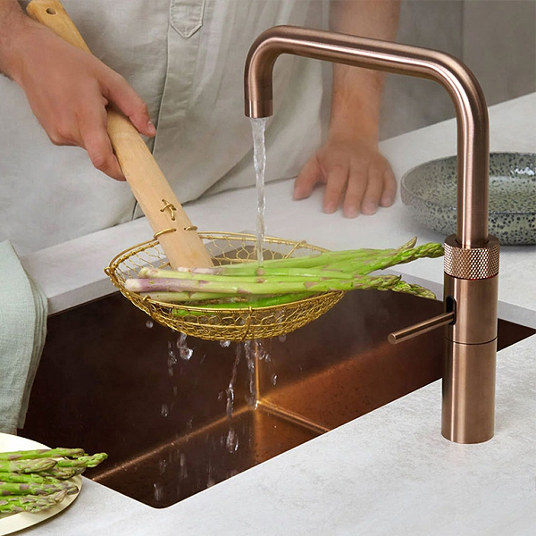 Quooker Fusion Square in Rosé Koper boven koperen spoelbak tijdens het afgieten van asperges