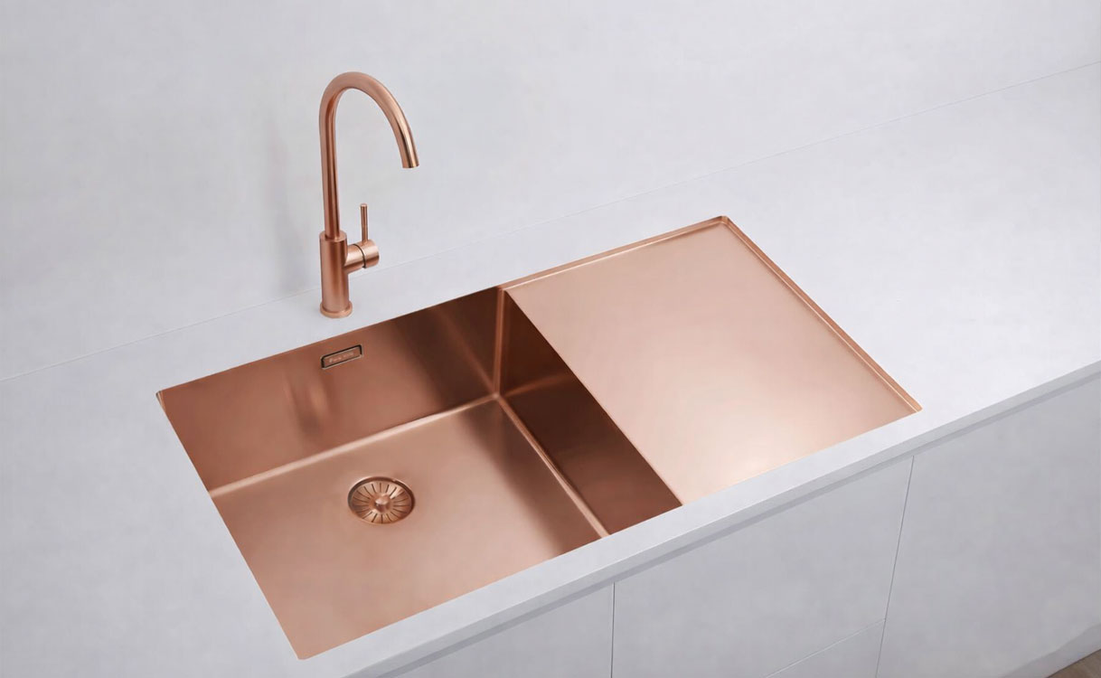Rosé gouden dubbele spoelbak met bijpassende kraan in een wit keukeneiland met strak werkblad