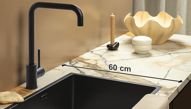 Marmerlook keukenblad met zwarte spoelbak en kraan, waarop de standaard diepte van een keukenblad van 60 cm wordt weergegeven