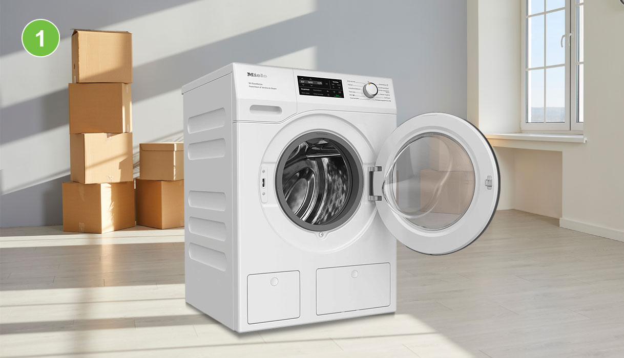 Witte Miele wasmachine met geopende deur in lege kamer met verhuisdozen op de achtergrond Titel: Stap 1: was