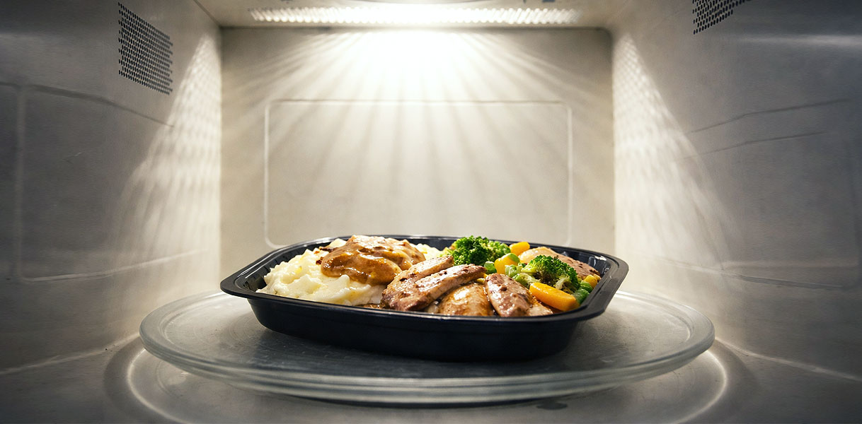 Warme maaltijd met vlees aardappelpuree en groenten die van binnenuit wordt opgewarmd in de magnetron