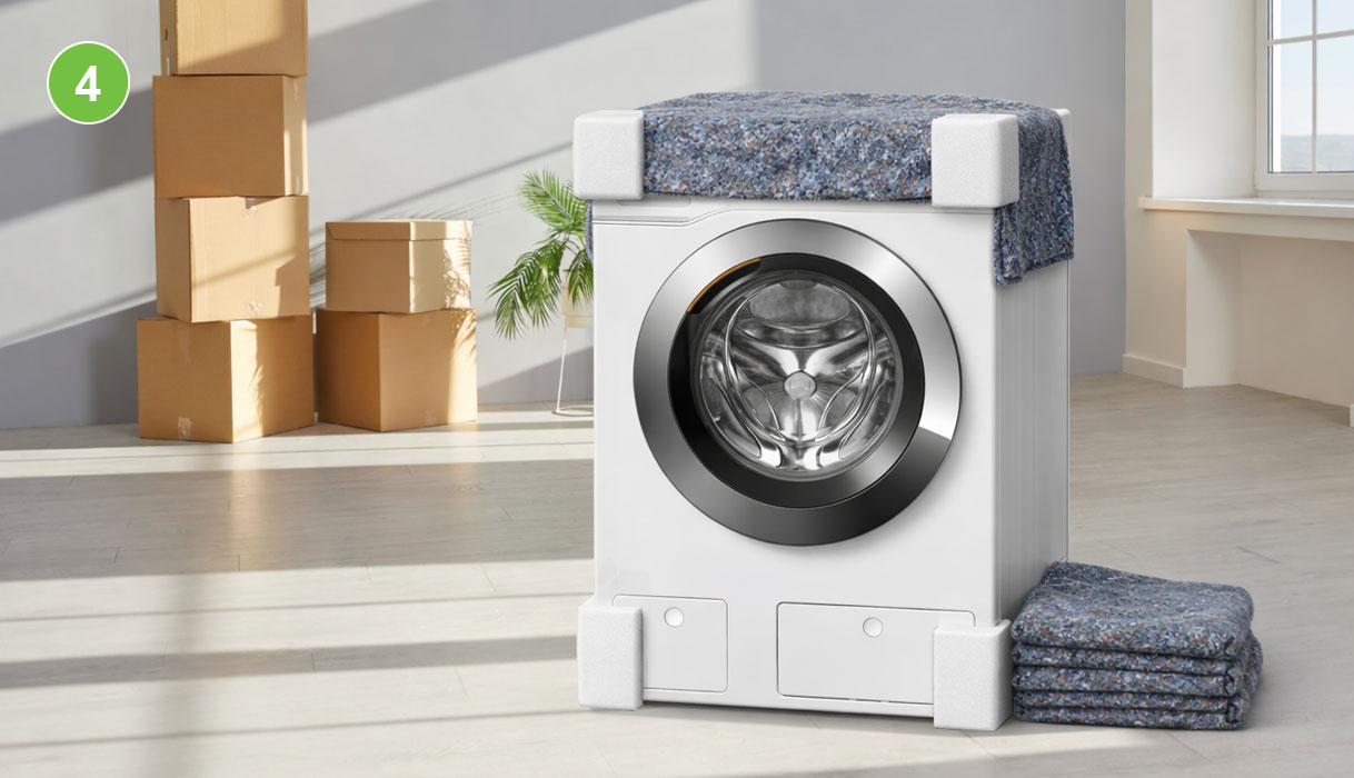 Wasmachine beschermd met verhuisdeken en piepschuim hoekbeschermers, verhuisdozen op de achtergrond