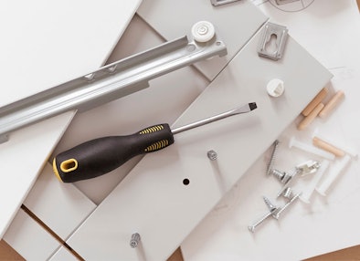 Keukenmonteur installeert kast en bevestigt scharnier met gereedschap in moderne keuken