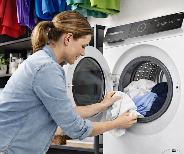 Droge kleding wordt in de wasmachinetrommel gelegd